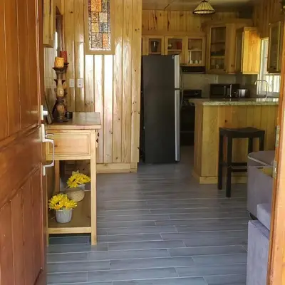 a kitchen with wooden cabinets and a black refrigerator at Villa Monte Alba in San Felipe de Puerto Plata