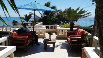 a man sitting in a chair under an umbrella on a patio at Ecolodge Vistamar in Los Patos