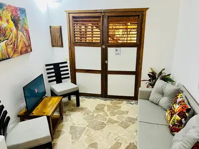 a living room with a couch and a chair and a door at La Cabañita de Jardín del Coco in Las Galeras