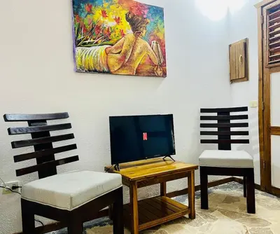 two chairs and a table with a tv and a painting at La Cabañita de Jardín del Coco in Las Galeras