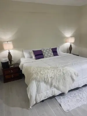 a bedroom with a large white bed with two lamps at Mayra House habitación independiente cerca del aeropuerto las Américas TAXI DISPONIBLE in Andrés