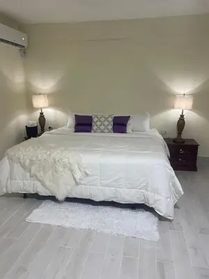 a bedroom with a large white bed with two lamps at Mayra House habitación independiente cerca del aeropuerto las Américas TAXI DISPONIBLE in Andrés