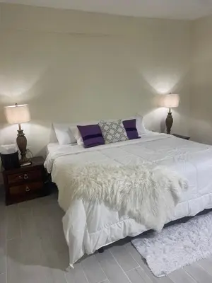 a bedroom with a large bed with white sheets and purple pillows at Mayra House habitación independiente cerca del aeropuerto las Américas TAXI DISPONIBLE in Andrés