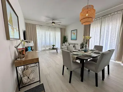 a dining room and living room with a table and chairs at Corner 2BDR in Coral Bay 2 in front of Hard Rock in Punta Cana