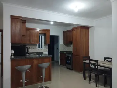 a kitchen with wooden cabinets and a table with chairs at Alojamiento Residencial MAM in San Cristóbal