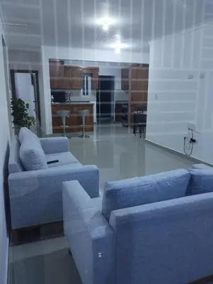 a living room with two blue couches and a kitchen at Alojamiento Residencial MAM in San Cristóbal