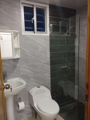 a bathroom with a toilet and a glass shower at Alojamiento Residencial MAM in San Cristóbal