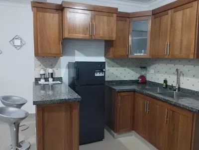 a kitchen with a black refrigerator and wooden cabinets at Alojamiento Residencial MAM in San Cristóbal