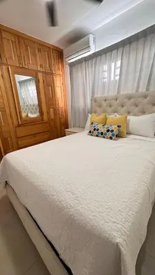 a bedroom with a large white bed with yellow and blue pillows at Coastal Apt, Near Malecón, 6 Guests 3 beds in La Romana