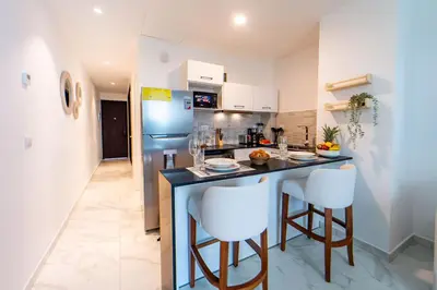 a kitchen with a counter and two white bar stools at Refugio Ideal Golf & Piscina Cana Rock Star in Punta Cana