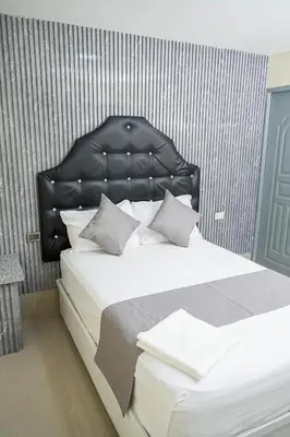 a bedroom with a bed with a black leather headboard at Hotel Monterio in Azua