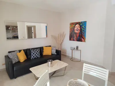 a living room with a black couch and a painting at Sunset Paradise Tracadero Apartment Sea pools access Private Garden WorkSpace in La Laguna