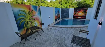 a pool with chairs and a painting on the wall at Hostal y Piscina in La Romana
