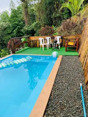 a swimming pool with two chairs and a table at Villa el privilegio in Jarabacoa