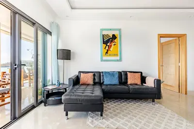 a living room with a black leather couch and a table at Modern Oceanview Retreat with Balcony and Walk to Bay in Santa Bárbara de Samaná