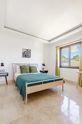 a white bedroom with a bed and a window at Modern Oceanview Retreat with Balcony and Walk to Bay in Santa Bárbara de Samaná