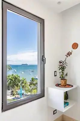 a window with a view of the ocean at Modern Oceanview Retreat with Balcony and Walk to Bay in Santa Bárbara de Samaná