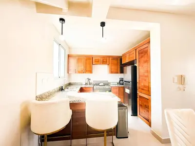 a kitchen with wooden cabinets and white counters at Serene Penthouse near Homs Hospital in El Ejido