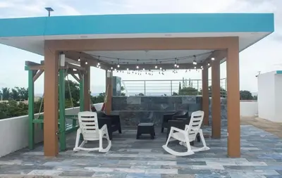 a pavilion with white chairs and a blue roof at Byk 2 in Nagua