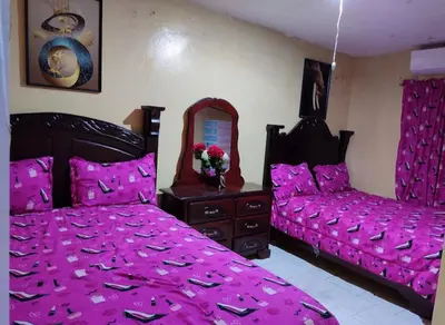 a bedroom with two beds with pink sheets and a mirror at Hotel Pensión la Hermosa Barahona in Santa Cruz de Barahona