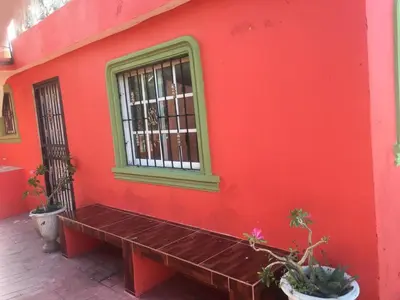 a red wall with a bench in front of a window at Hotel Pensión la Hermosa Barahona in Santa Cruz de Barahona