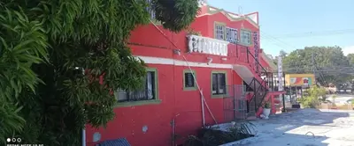 a red building with a tree in front of it at Hotel Pensión la Hermosa Barahona in Santa Cruz de Barahona