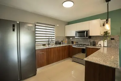 a kitchen with a stainless steel refrigerator and wooden cabinets at The Jade Lodge 2BR Apartment- Enjoy the nature in Puerto Plata