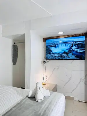 a bedroom with a bed with a tv on the wall at Estudio Elegante 10 minutos del Monumento & Agora mall in Santiago de los Caballeros