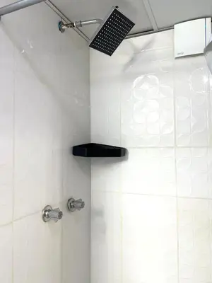 a shower with a black seat in a bathroom at Estudio Elegante 10 minutos del Monumento & Agora mall in Santiago de los Caballeros