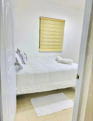 a white bedroom with a bed with a window at Apartment with Everything AC Wifi and Solar panel in Bonao