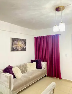 a living room with a couch and red curtains at Apartment with Everything AC Wifi and Solar panel in Bonao