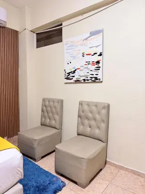 two chairs in a room with a bed and a painting at Habitaciónes suite 10 min del Monumento & Agora Mall in Santiago de los Caballeros