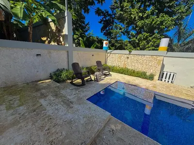 a swimming pool with two chairs next to a fence at Villa Palmera Barahona, Dream Getaway in Santa Cruz de Barahona