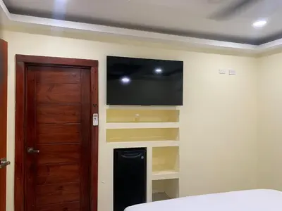 a bedroom with a flat screen tv and a door at Villa Palmera Barahona, Dream Getaway in Santa Cruz de Barahona