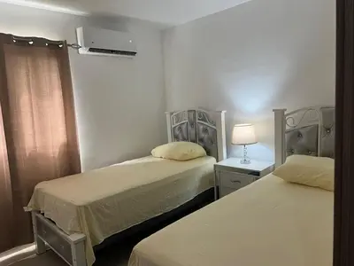 a room with two beds and a lamp and a window at The perfect destination to relax in Santiago de los Caballeros