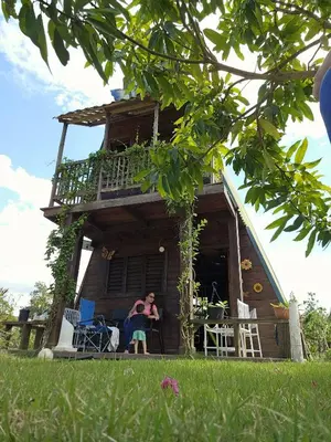 a woman sitting on the porch of a house at Mi casita de Campo en Bayaguana in Bayaguana