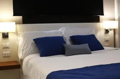 a white bed with blue pillows and two lamps at 1BRM Infinity Homes Punta Cana in Punta Cana