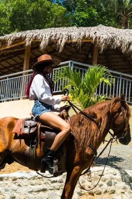a woman riding a horse in front of a hut at Villa María 2 in Bonao