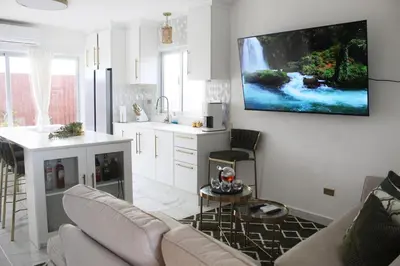 a living room with a couch and a tv on a wall at Casaè Rojas Presents Golden Oasis in Punta Cana