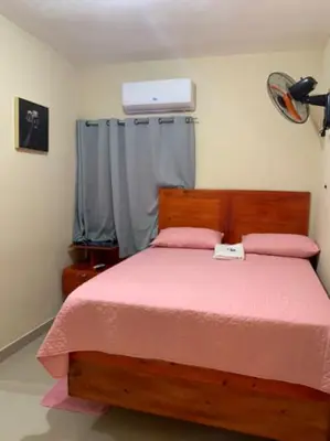 a bedroom with a wooden bed with a pink blanket at Hotel los 4 Tesoros in Pedernales