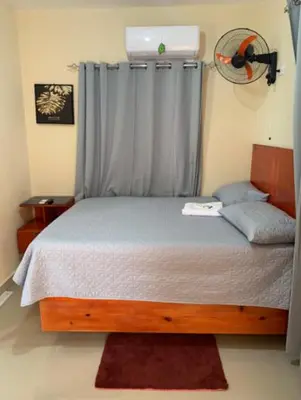 a bedroom with a bed with a window with a fan at Hotel los 4 Tesoros in Pedernales