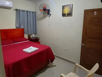 a bedroom with a bed with a red blanket and a chair at Hotel los 4 Tesoros in Pedernales