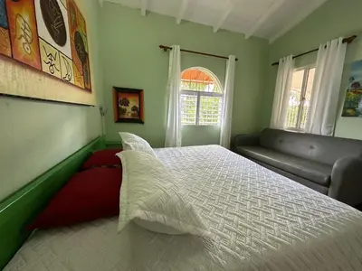 a bedroom with a white bed and a couch at Casa pintada - 4 people, 4 minutes from the beach in Las Galeras
