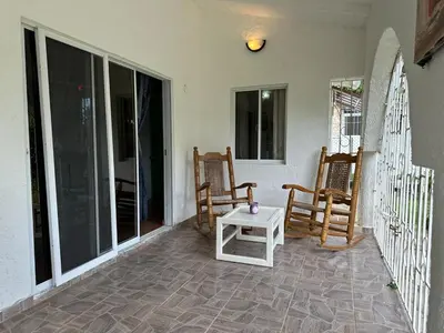 a patio with rocking chairs and a table on a porch at Casa pintada - 4 people, 4 minutes from the beach in Las Galeras