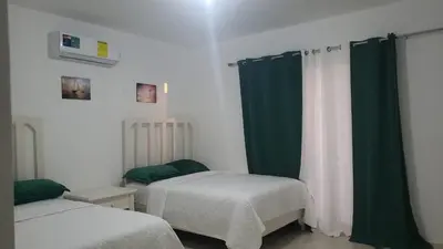 a bedroom with two beds and green curtains at Hotel Dieux Internacional in Pedernales