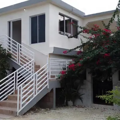 a white house with stairs and flowers at Hotel Dieux Internacional in Pedernales