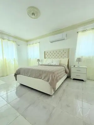 a white bedroom with a large bed and white tile floors at Residencial Marvin I Apartamento 1A in Santiago de los Caballeros