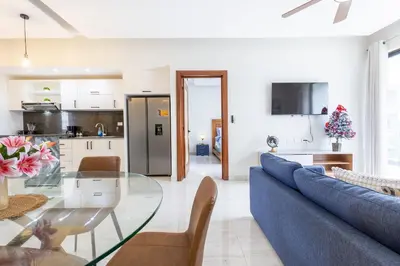 a living room with a blue couch and a glass table at Quiet 1-Bedroom Apartment with Pool View in Gated Bávaro Residence in Punta Cana