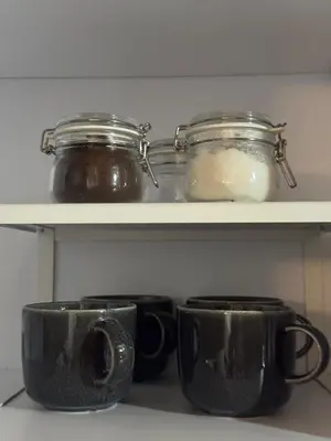 two black coffee cups and jars on a shelf at Apartment bayahibe in Bayahibe