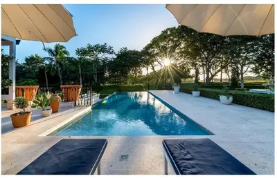 a swimming pool with an umbrella in a yard at Luxury Awaits at Casa de Campo A Stunning Five-Bedroom Retreat in La Romana